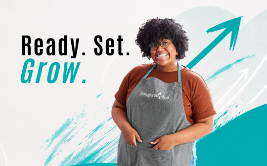 Pampered Chef Beraterin mit Schürze vor „Ready. Set. Grow.“-Motiv als Einladung, mit Pampered Chef persönlich und beruflich zu wachsen.
