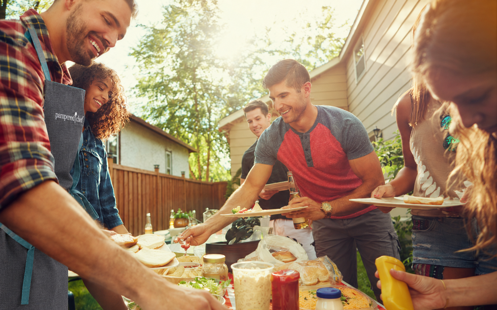 Menschen bereiten gemeinsam Speisen im Garten zu und genießen eine sommerliche Kochshow im Freien. Das Bild vermittelt Gemeinschaft, Genuss und die Freude am gemeinsamen Kochen.
